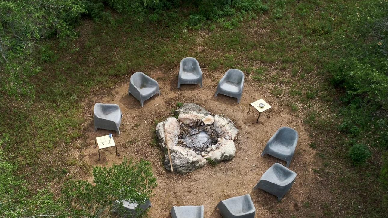 The fire circle from above, a ring of seats held in a clearing among the oaks